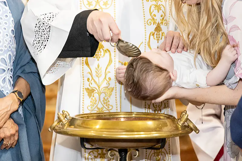 Fotografo battesimo Milano: neonato durante il rito in chiesa