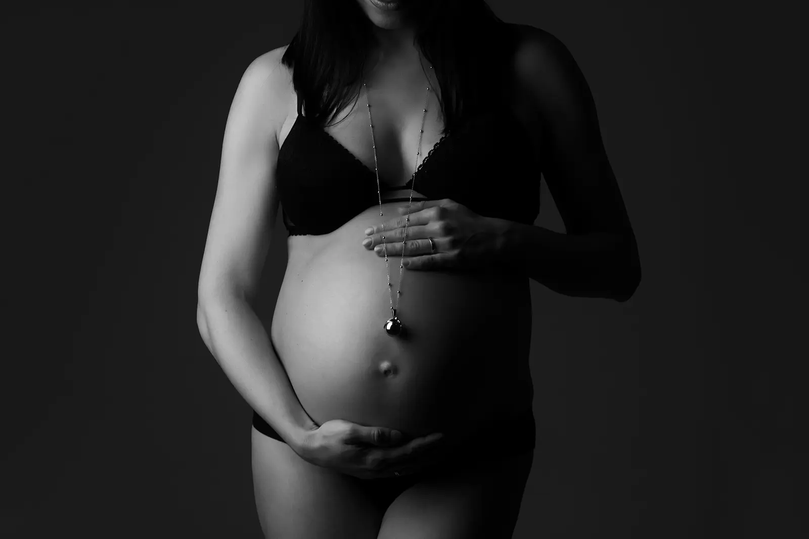 Foto gravidanza in bianco e nero, futura mamma con collana bola, ritratto in studio a Milano