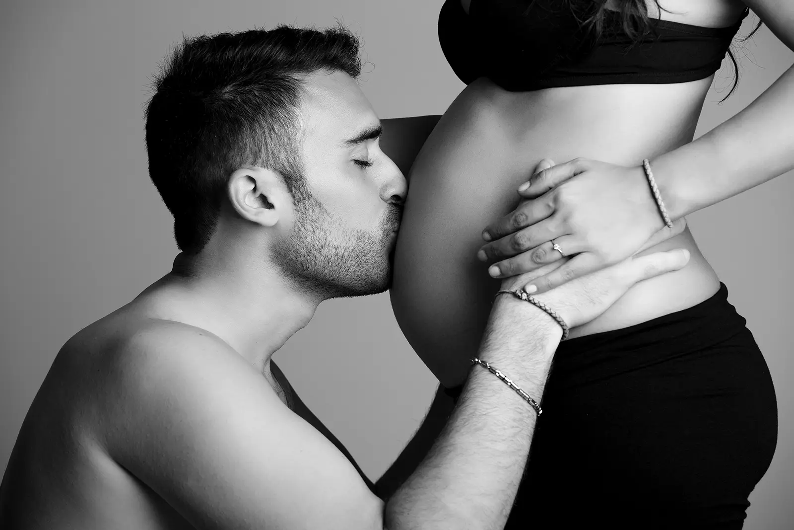 Abbraccio intimo di una coppia in attesa, fotografia in bianco e nero in studio a Milano