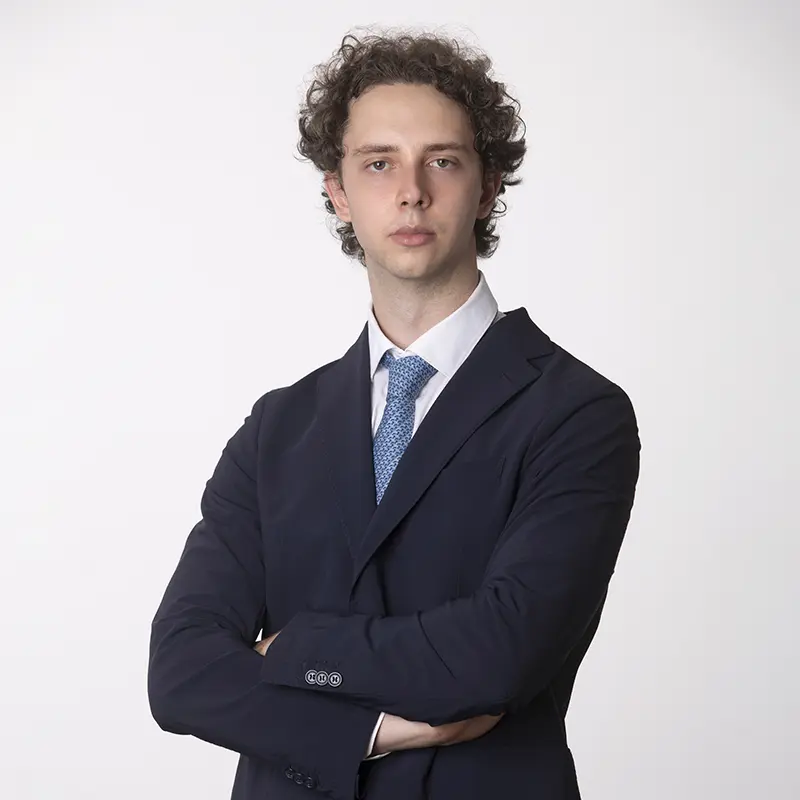 Foto profilo LinkedIn uomo con capelli ricci in abito blu e cravatta azzurra, studio Milano
