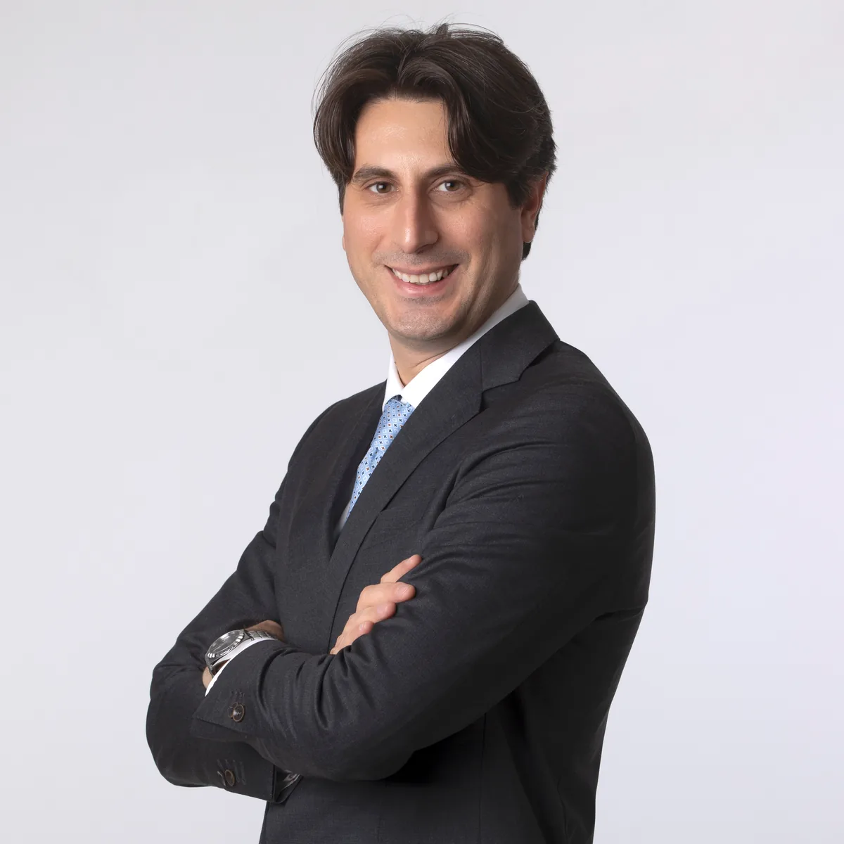 Foto profilo LinkedIn di un uomo sorridente in abito scuro e cravatta azzurra, studio a Milano