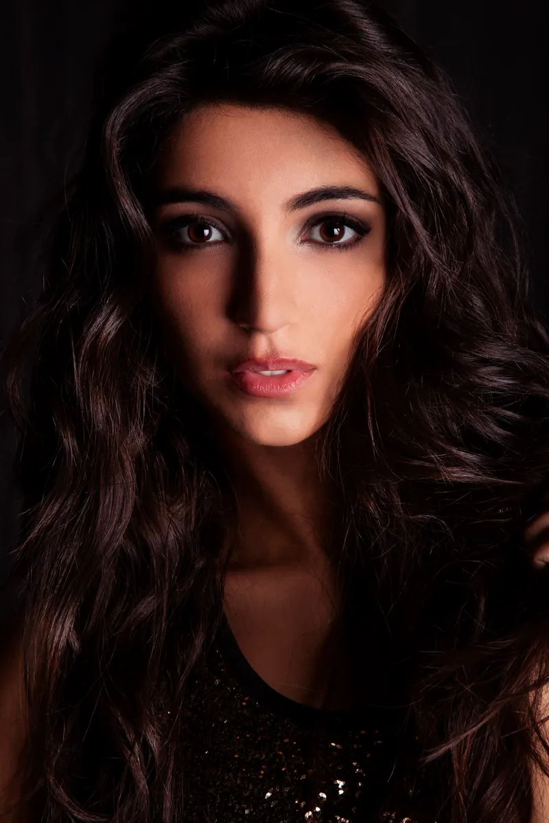 Ritratto fotografico donna in studio a Milano, primo piano su fondo scuro con luce morbida